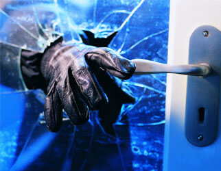 Burglar gloved hand smashing window glass during home break-in — stopped by ArmourCore window security film